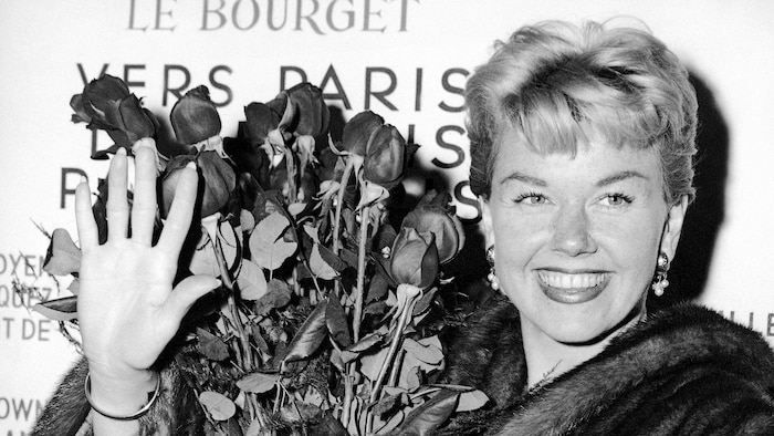 FILE - In this April 15, 1955 file photo, American actress and singer Doris Day holds a bouquet of roses at Le Bourget Airport in Paris, France after flying in from London. Day, whose wholesome screen presence stood for a time of innocence in '60s films, has died, her foundation says. She was 97. The Doris Day Animal Foundation confirmed Day died early Monday, May 13, 2019, at her Carmel Valley, California, home. (AP Photo, File)
