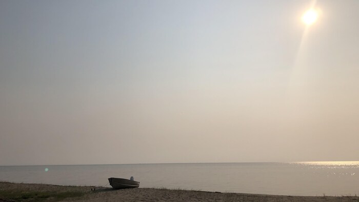 Un nuage de smog surplombe le lac Saint-Jean et une plage. 