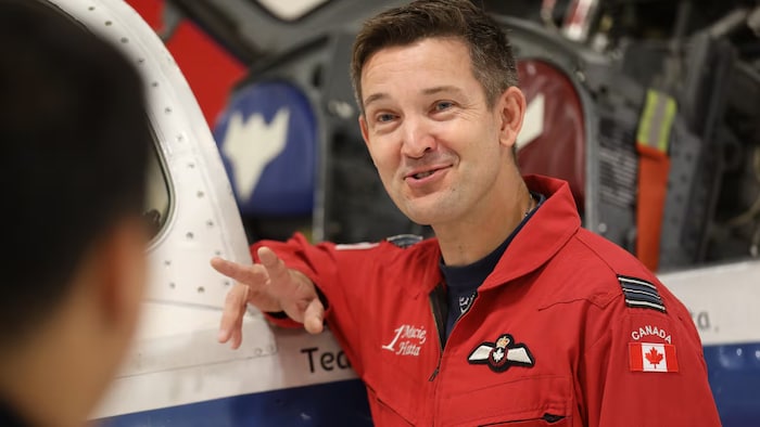 Un membre des Snowbirds habillé de rouge parle avec une autre personne.
