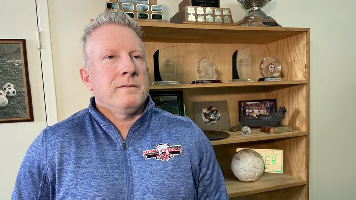 Homme debout devant un meuble rempli de trophées