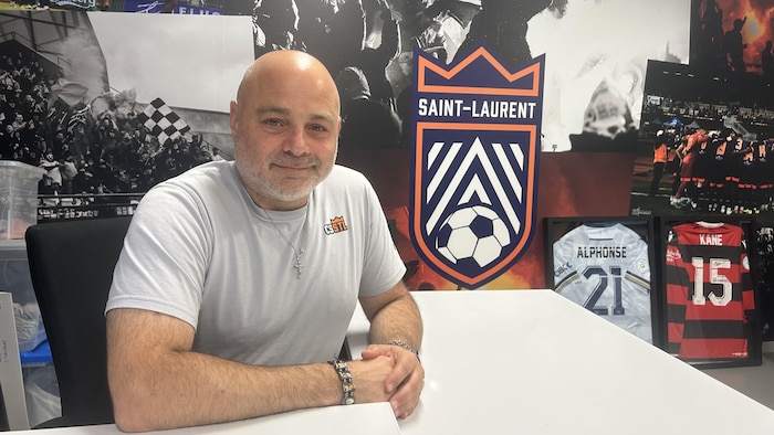 Un homme pose pour la caméra dans son bureau.