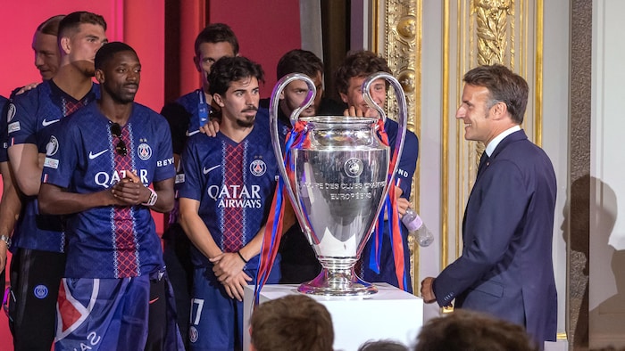 Le président français, Emmanuel Macron, devant les joueurs et leur trophée.
