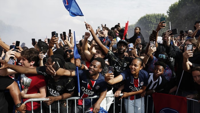Des partisans derrière une barrière tentent de prendre en photo les joueurs de l'équipe.