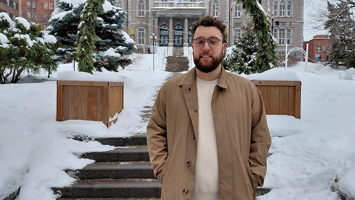 Charles Picard-Duquette se tient debout dans la neige, devant l'hôtel de ville.