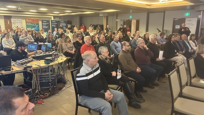 Une foule de gens assis dans une salle.