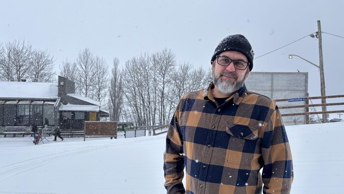 Un homme pose en chemise sous la neige. 