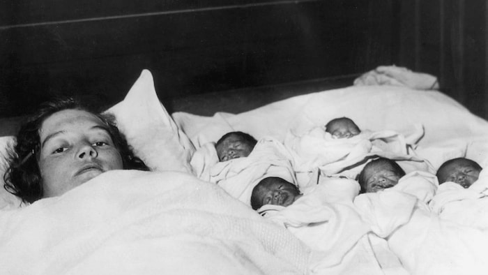 Les bébés avec leur mère dans des draps sur un lit après leurs naissances.