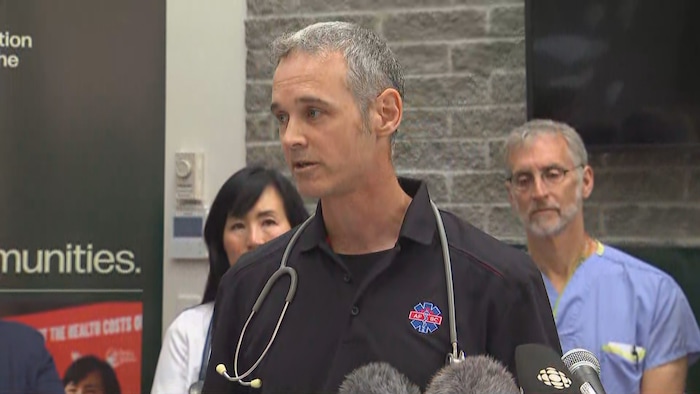 Un ambulancier en tenue donne une conférence de presse.