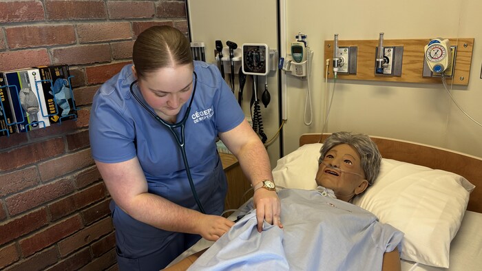 Thalie Misson utilise son stéthoscope sur un mannequin médical.