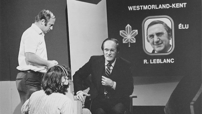 Le présentateur Gabi Drouin devant un écran dévoilant que R. Leblanc est élu dans la circonscription de Westmorland-Kent.