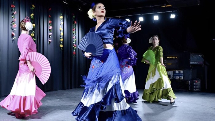 trois femmes vêtues de costumes traditionnels flamenco son sur scène durant un spectacle.