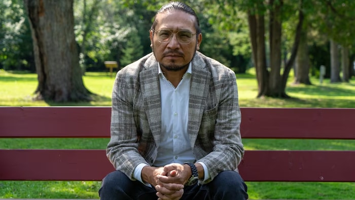 Le député Sol Mamakwa assis dans un parc.