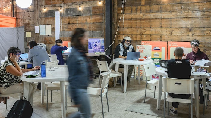 Des militants avec des ordinateurs assis à des tables de plastique blanc.
