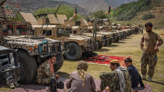 Quelques hommes sont installés près de véhicules tout-terrain fournis par l'armée américaine dans une région montagneuse. 