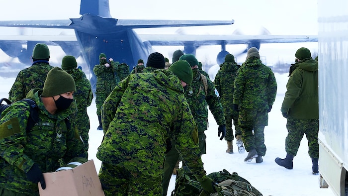 Des soldats canadiens s'apprêtant à monter dans un avion, en hiver.