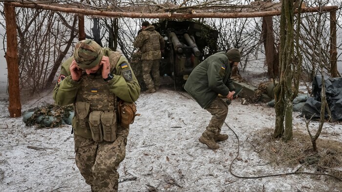 Des soldats des forces armées ukrainiennes tirent un obus.