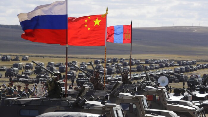 Des drapeaux russe, chinois et mongol installés sur des véhicules militaires.