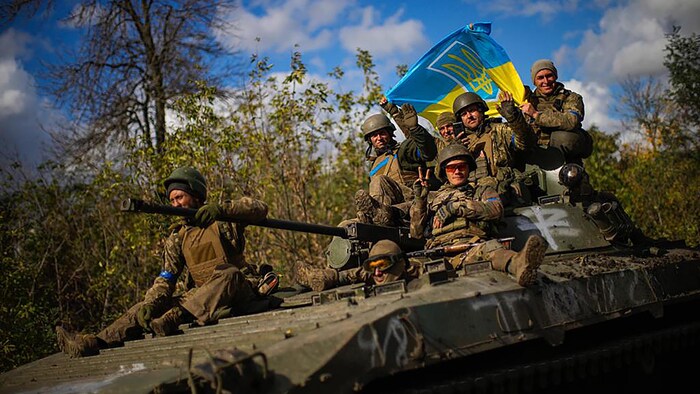 Ukrainian soldiers sit on an armoured vehicle as they drive on a road between Izium and Lyman in Ukraine on Tuesday. 