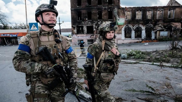 Un soldat ukrainien, accompagné d’une soldate, lève les yeux au ciel après avoir entendu le bruit d’un drone lors d’une patrouille à Kupiansk, ville située en première ligne dans la région de Kharkiv, le 24 septembre 2022, en pleine invasion russe de l’Ukraine.