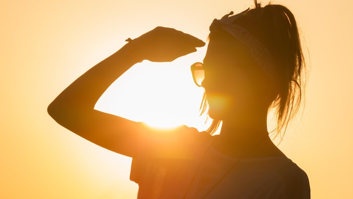 Une femme expose son visage au soleil.