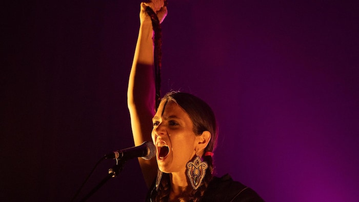 Une chanteuse lève un bras sur scène.