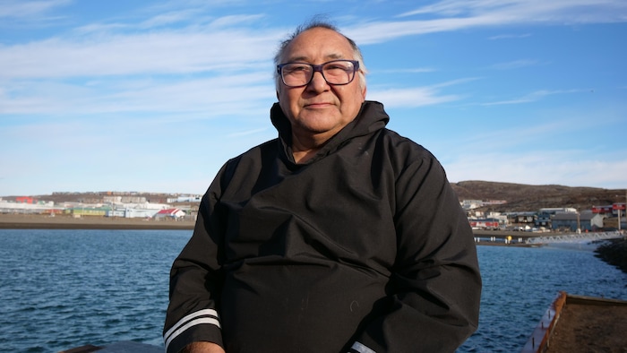 Un homme devant une vue d'Iqaluit, en octobre 2023.