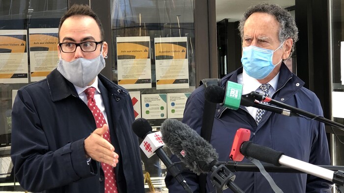 Deux hommes masqués devant les micros des journalistes.