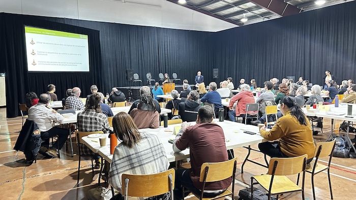 Une salle communautaire remplie de participants à un sommet sur les changements climatiques.
