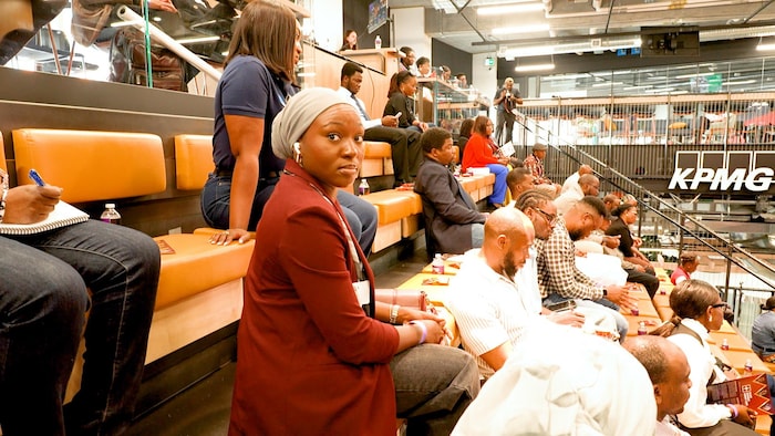Plusieurs personnes sont assises sur des bancs dans une salle de spectacle.