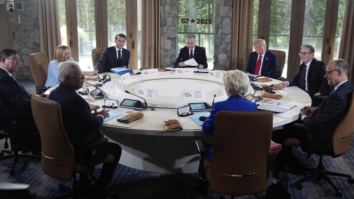 Les dirigeants sont réunis autour d'une table devant une  fenêtre. 