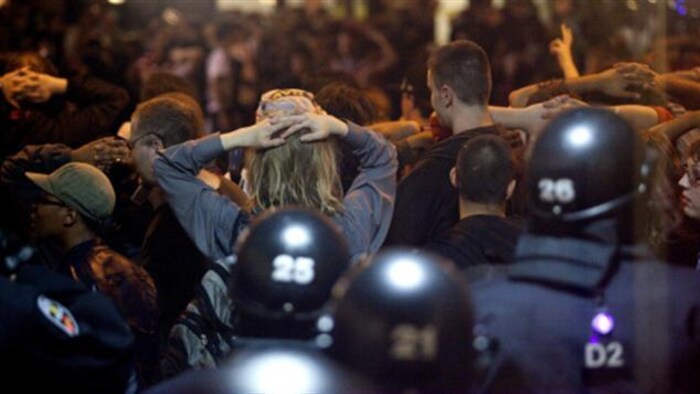 Des civils arrêtés par la police, les mains sur la tête.