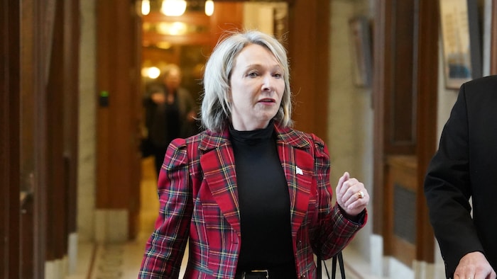 Sonia Bélanger marche dans un corridor de l'Assemblée nationale en compagnie d'un homme.