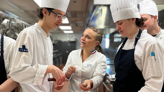 Sonia Bichet montre à des étudiants en cuisine à ouvrir des huîtres.