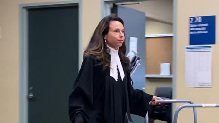 La femme portant une toge sort de la salle d'audience.