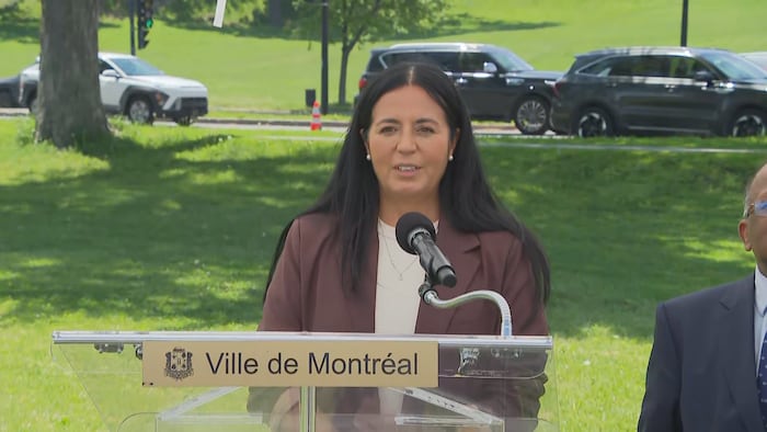Soraya Martinez Ferrada derrière un lutrin de la Ville de Montréal lors d'une conférence de presse dans un parc.