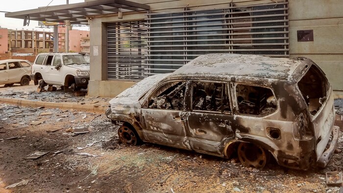Une voiture calcinée à côté d'un édifice.