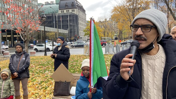 Un homme parle au microphone dans une place publique.