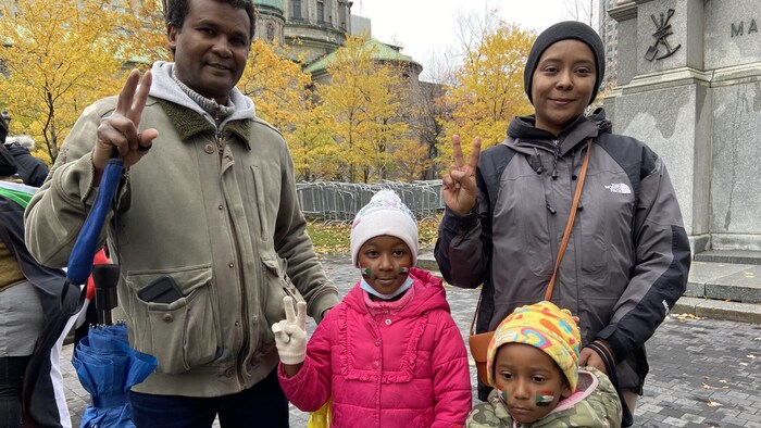 Un homme, une femme et leurs deux petites filles font le signe de la victoire.