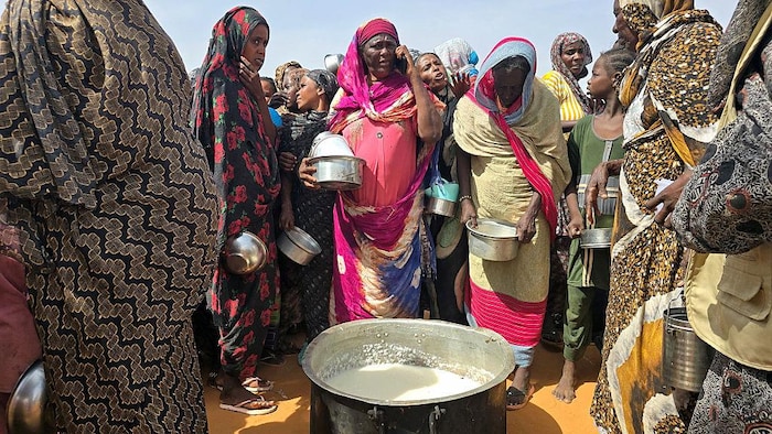 Des femmes soudanaises se rassemblent pour prendre un repas dans une chaudière au sol.