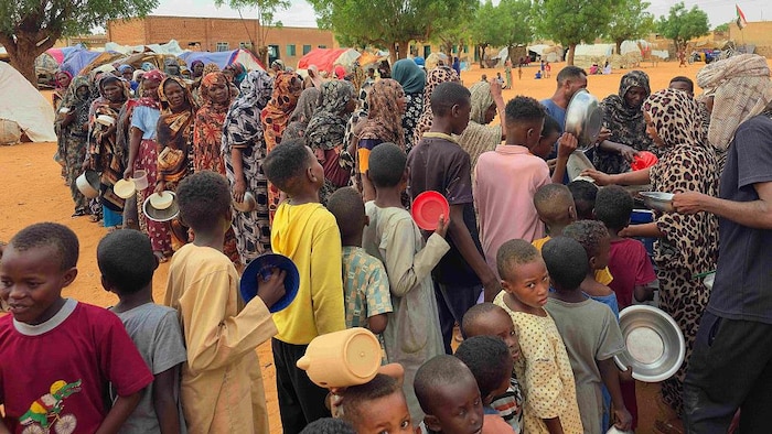 Des femmes et des enfants font la queue pour recevoir de la nourriture.
