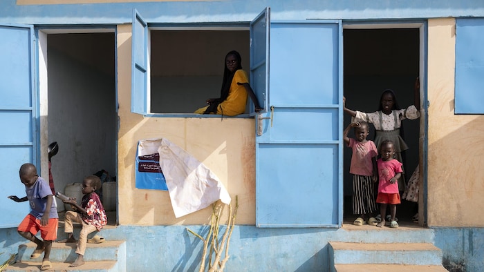 Des enfants posent dans l'encadrement des portes d'une maison.
