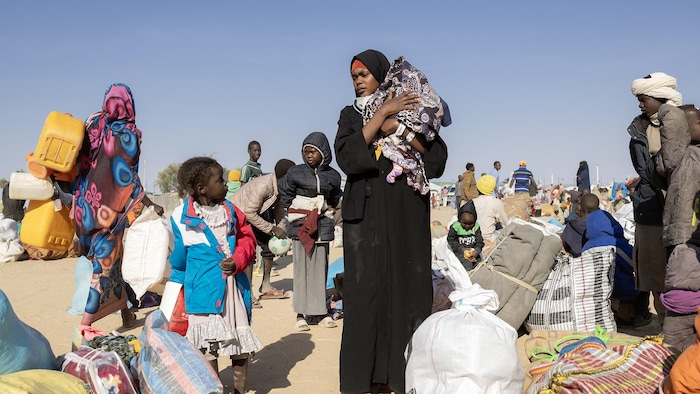 Une femme et ses enfants avec des bagages dans un camp de réfugiés.