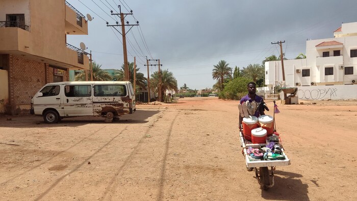 Un homme pousse une charrette dans une rue de Khartoum.