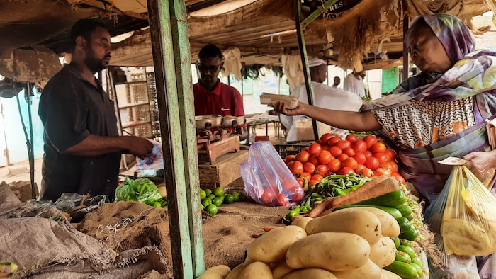 Une femme achète des légumes dans un marché au Soudan.