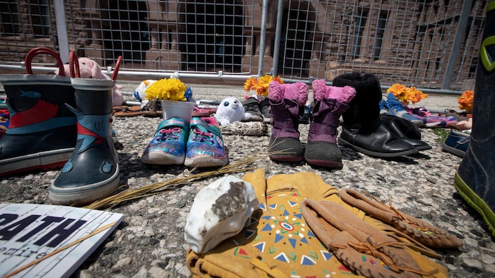 Des souliers d'enfants et d'autres objets déposés à Queen's Park en mémoire des élèves morts au pensionnat pour Autochtones de Kamloops.
