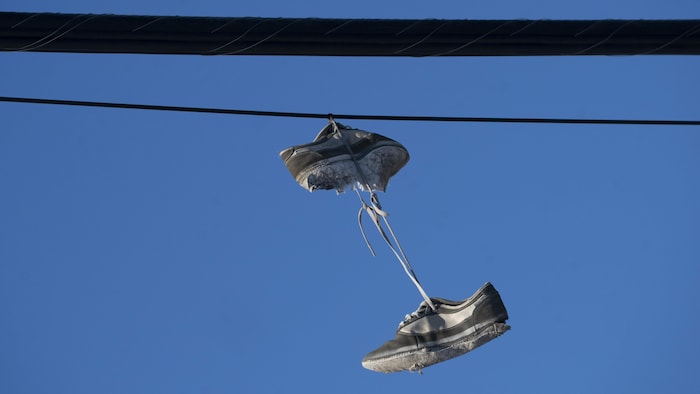 Des souliers sont suspendus à des fils électriques. 