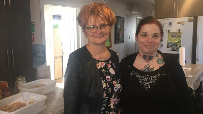 Deux femmes sourient à la caméra dans une cuisine.