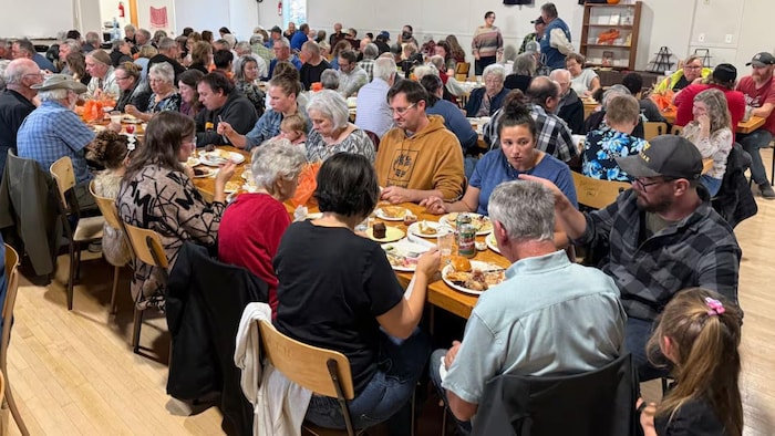 Des participants se rassemblent autour d'un grand buffet communautaire à Weirdale en Saskatchewan.
