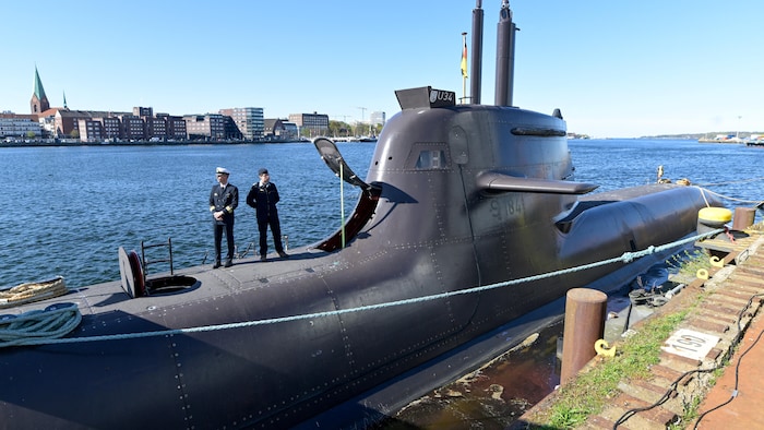 Deux hommes sont sur un sous-marin U-34 amarré dans un chantier naval.