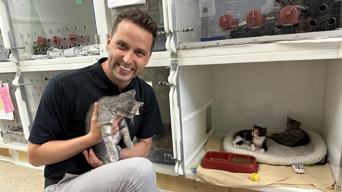Un homme à genou tient un chat dans ses bras.